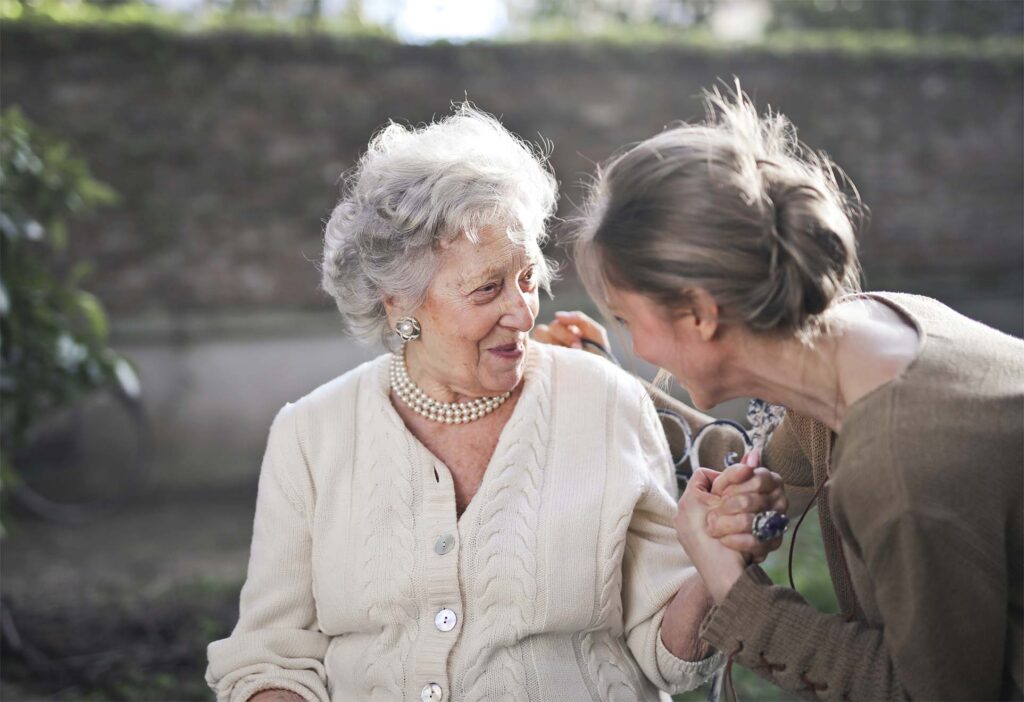 elderly woman laughing outdoors with her daughter