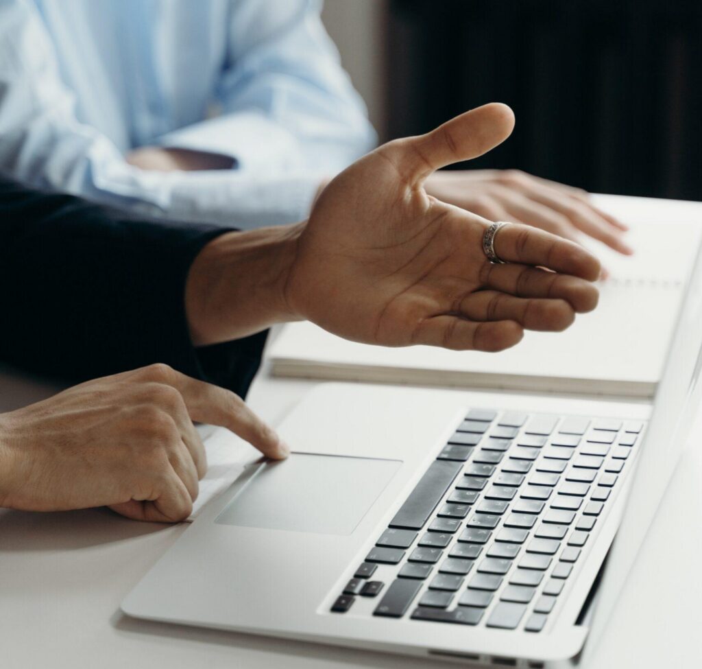 man explaining with hand extended while using a laptop